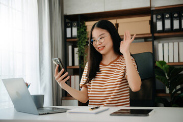 Young attractive Asian woman smiling thinking planning writing in notebook, tablet and laptop working from home, at office