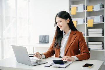 Young beautiful woman typing on tablet and laptop while sitting at the working wooden table office.