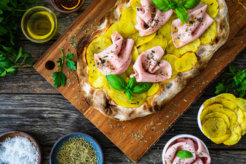 Mortadella and potato pizza on wooden table