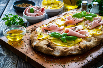 Mortadella and potato pizza on wooden table