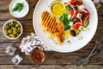 Seared chicken breast and Greek salad on wooden table

