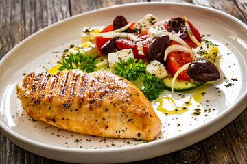 Seared chicken breast and Greek salad on wooden table
