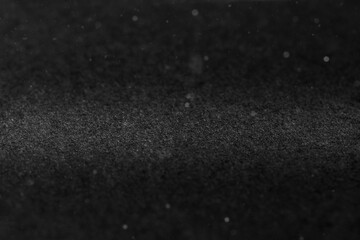 Black abstract paper background with highlights and sparkles.