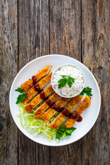 Tonkatsu - crispy Japanese pork chop with white rice and  fresh vegetables on wooden table