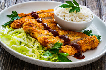 Tonkatsu - crispy Japanese pork chop with white rice and  fresh vegetables on wooden table