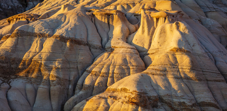 Close-up in panorama format of the barren eroded hills in the badlands along the Deer River in the vicinity of Drumheller, at sunset Canada