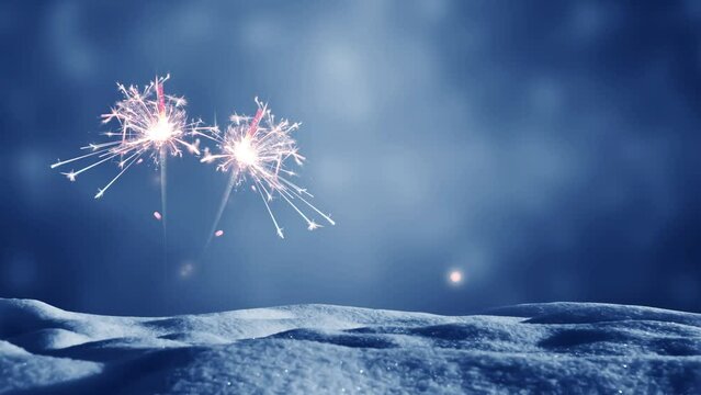 two burning sparkler in snow on abstract blurred blue sky background with copy space for festive holidays like happy new year, new years eve or christmas celebration 