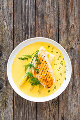 Grilled chicken breast and white asparagus in hollandaise sauce on wooden table
