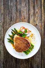 Grilled beef steak with green asparagus on wooden table


