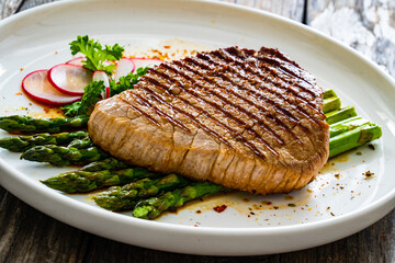 Grilled beef steak with green asparagus on wooden table

