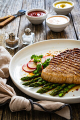 Grilled beef steak with green asparagus on wooden table

