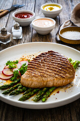 Grilled beef steak with green asparagus on wooden table

