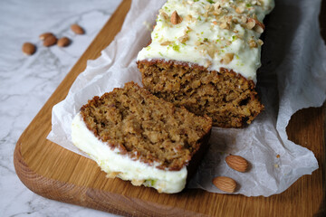 Delicious carrot cake with walnuts and almonds with icing cream on a light background. Baking concept. Selective focus. Homemade baking.