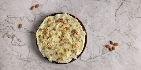 Delicious carrot cake with walnuts and almonds with icing cream on a light background. Baking concept. Selective focus. Homemade baking.