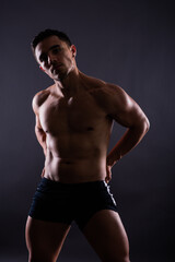 Fototapeta na wymiar Muscular shirtless young man standing confident, front view, looking at camera