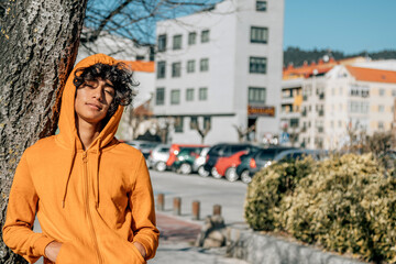 Obraz premium casual teenager with sweatshirt leaning on a tree in the street