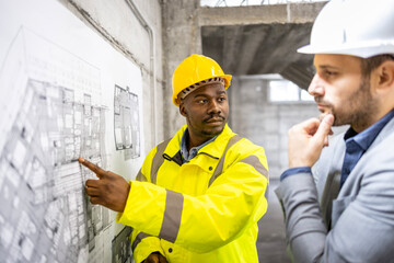 Construction worker showing foundation on the blueprint to the structural engineer.