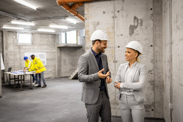 Architect and interior designer visiting construction site and discussing about new project plan.