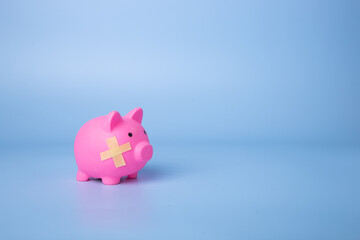Piggy bank with band aid bandage in blue background.