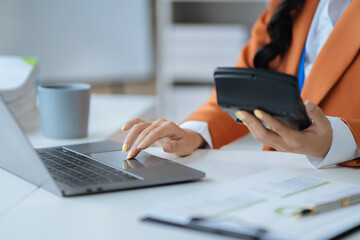 Business women or accountant working on laptop computer with business document, graph diagram and calculator on office table in office.