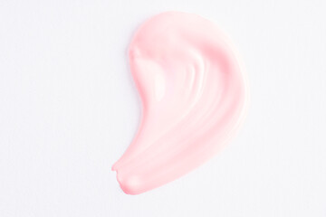 Pink cosmetic cream smear on white background. Pink beauty cream smear swipe swatch closeup. Skincare product macro. Light pink paint swatch