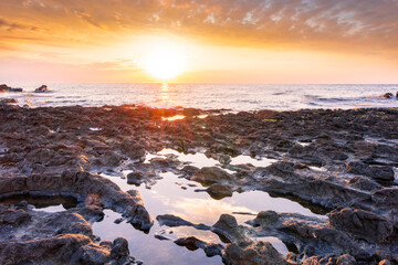 beautiful golden sunset or sunrise on a seashore bank with blue sea water and yellow sunnny evening cloudy sky