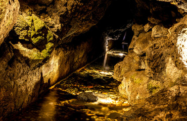 underground cave with cellar in rock with yellow lights and subterranean river