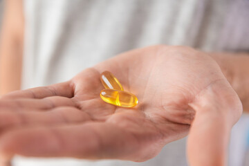 Fish oil capsules with omega 3, vitamin D in male hand. Nutritional supplement, medicine, drug for health care.
