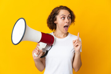 Young English woman isolated on yellow background holding a megaphone and intending to realizes the...
