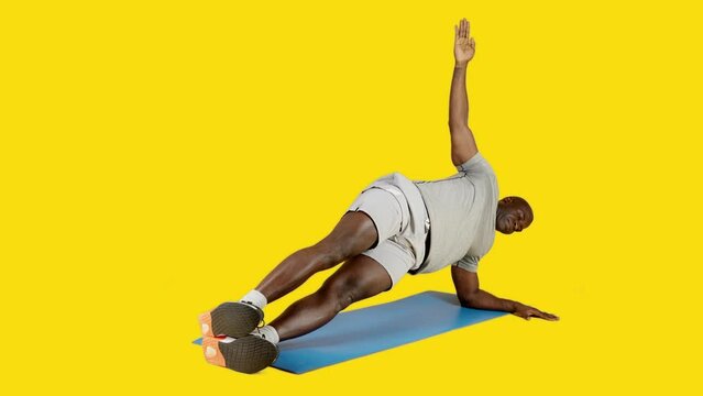Sportive african man doing lateral plank exercise on a mat