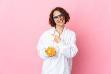 Young English scientific woman isolated on pink background pointing to the side to present a product