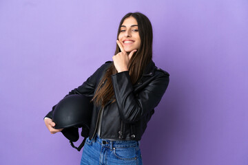 Young caucasian woman with a motorcycle helmet isolated on purple background happy and smiling
