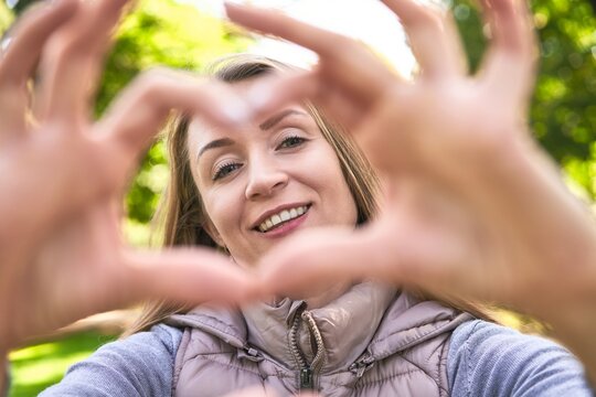 Joyful woman forming a heart, her smiling face the picture of happiness.