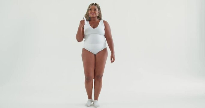 funny beautiful African plus size smiling young woman in swimsuit dancing in the white background waving a fan. studio. slow motion. lifestyle free spare time. copy space entertainment