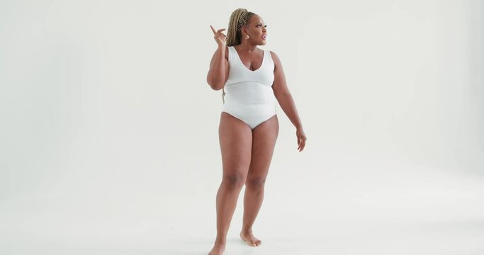 cool stylish plump sexy American woman hanging out at white studio, dancing to favourite music while being in a perfect mood Slow motion, girl pointing to the side