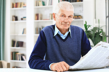 Portrait of an old man solving crosswords in the newspaper