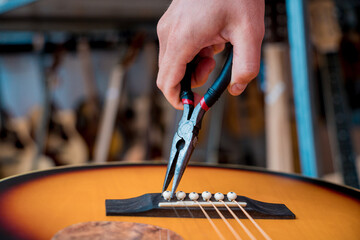Young musician changing strings on a classical guitar in a guitar shop