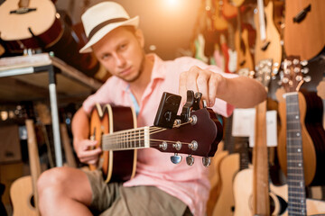 Young musician tuning a classical guitar in a guitar shop