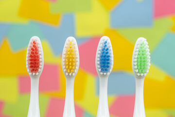 Red, yellow, blue and green toothbrushes with multicolored paper sticky notes on background