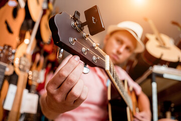 Young musician tuning a classical guitar in a guitar shop