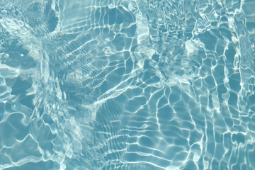 Blue water with ripples on the surface. Defocus blurred transparent blue colored clear calm water surface texture with splashes and bubbles. Water waves with shining pattern texture background.