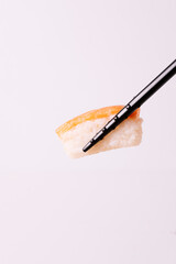 Portion of nigiri caught with black chopsticks.