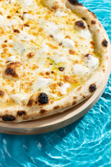 hot pizza on a wooden stand on a blue background water