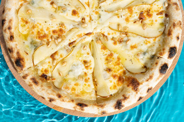 hot pizza on a wooden stand on a blue background water