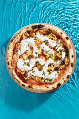 hot pizza on a wooden stand on a blue background water