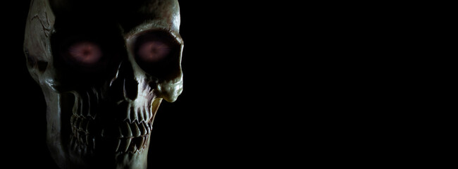 Human skull with purple glowing eyes with copy space