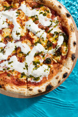 hot pizza on a wooden stand on a blue background water