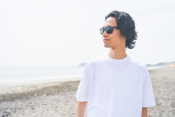夏の海岸を歩くサングラスをかけた男性