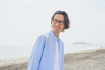 海岸を歩く青いストライプシャツを着た男性