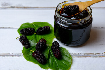 Mulberries fruit, mulberry molasses and fresh mulberry in glass bowl, wooden background.